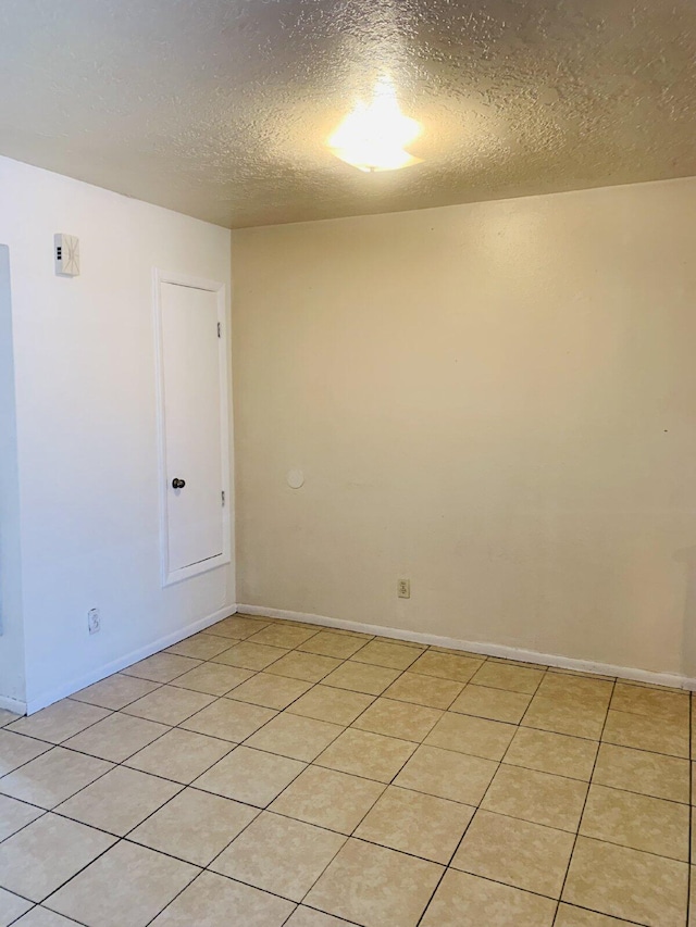 tiled empty room featuring a textured ceiling