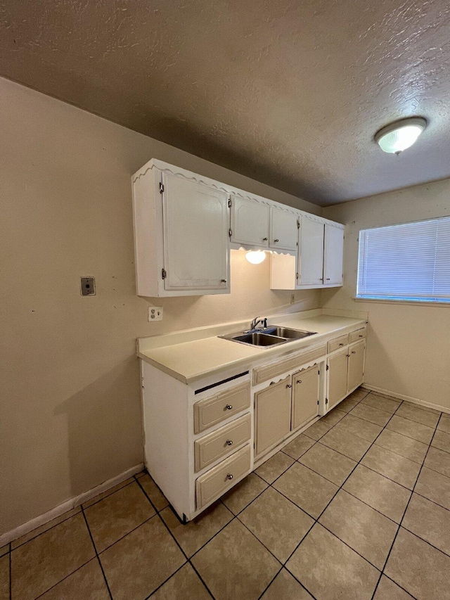 kitchen featuring white cabinetry, sink, light tile patterned floors, and a textured ceiling