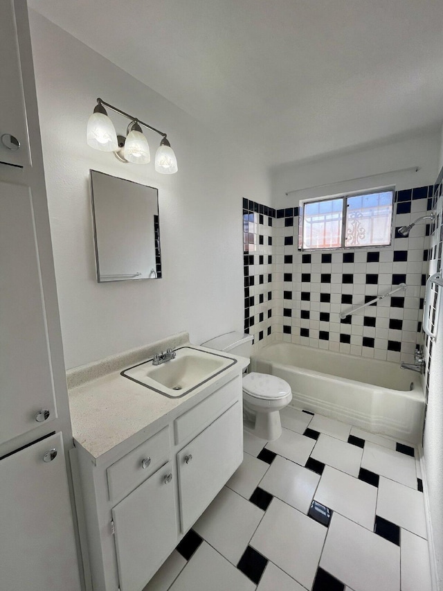 full bathroom featuring tiled shower / bath, vanity, and toilet