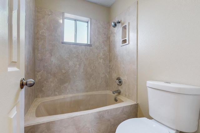 bathroom featuring tiled shower / bath and toilet