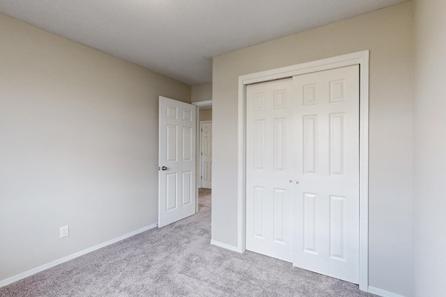 unfurnished bedroom featuring light colored carpet and a closet