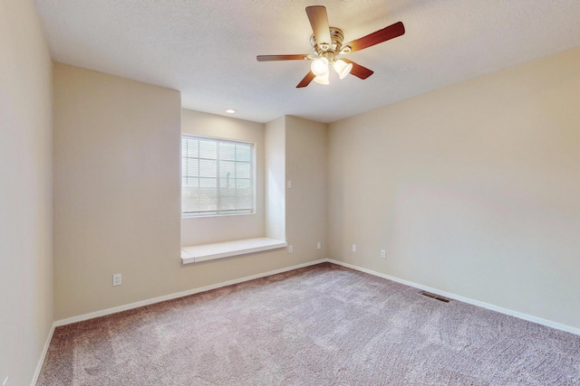 spare room with a textured ceiling, carpet floors, and ceiling fan