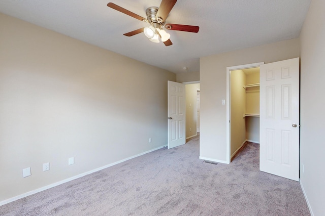 unfurnished bedroom featuring ceiling fan, light colored carpet, a spacious closet, and a closet