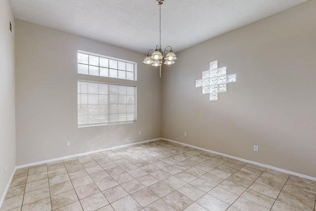 tiled empty room with a textured ceiling and a notable chandelier