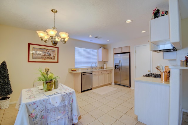 kitchen with light tile patterned flooring, appliances with stainless steel finishes, pendant lighting, sink, and a chandelier