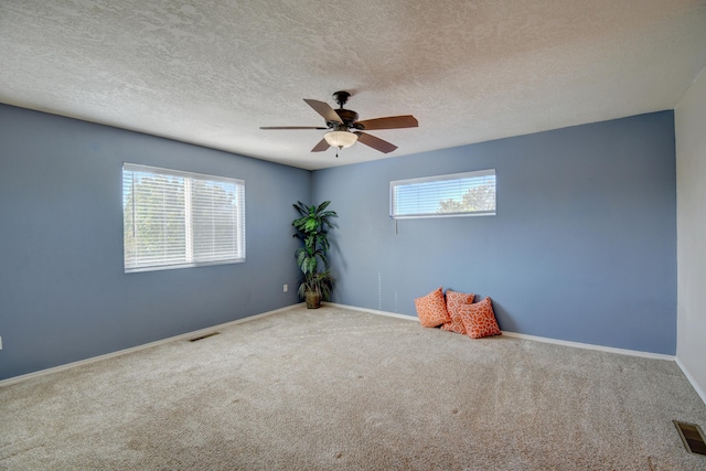 carpeted spare room featuring ceiling fan and a textured ceiling