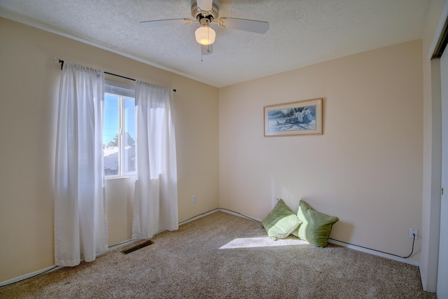 unfurnished bedroom with a textured ceiling, light colored carpet, and ceiling fan