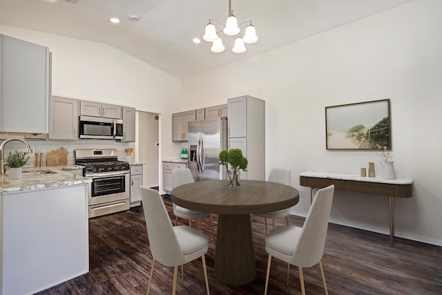 dining room featuring vaulted ceiling, an inviting chandelier, dark wood-type flooring, and sink