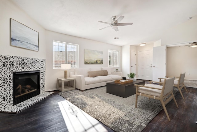 living room with ceiling fan, dark wood-type flooring, and a tile fireplace