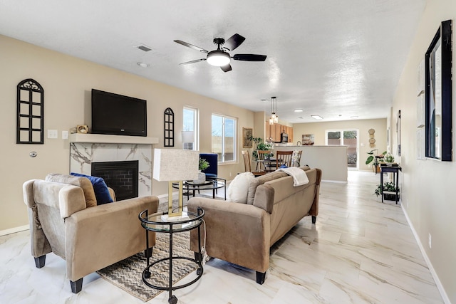 living room with a fireplace, plenty of natural light, and ceiling fan