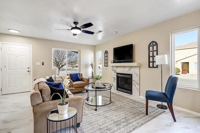 living room with a fireplace, a wealth of natural light, a textured ceiling, and ceiling fan