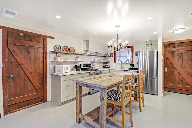 kitchen with backsplash, light countertops, a barn door, stainless steel appliances, and open shelves