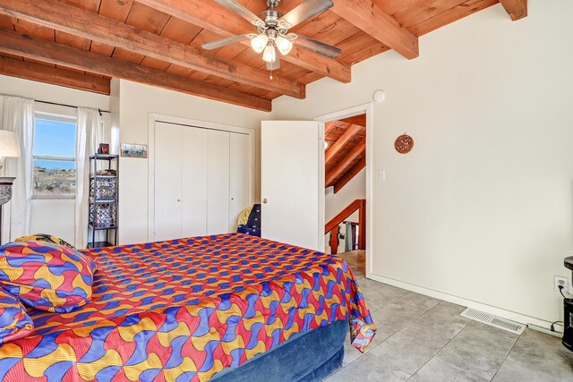 bedroom with ceiling fan, a closet, beamed ceiling, and wooden ceiling