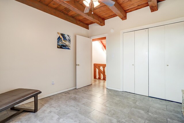 unfurnished bedroom with ceiling fan, beam ceiling, wood ceiling, and a closet