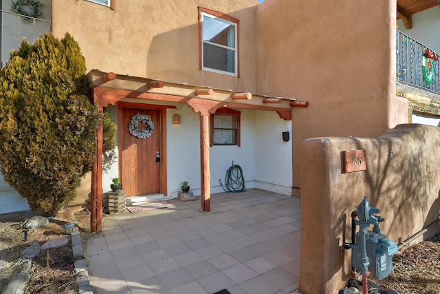 doorway to property featuring stucco siding and a patio