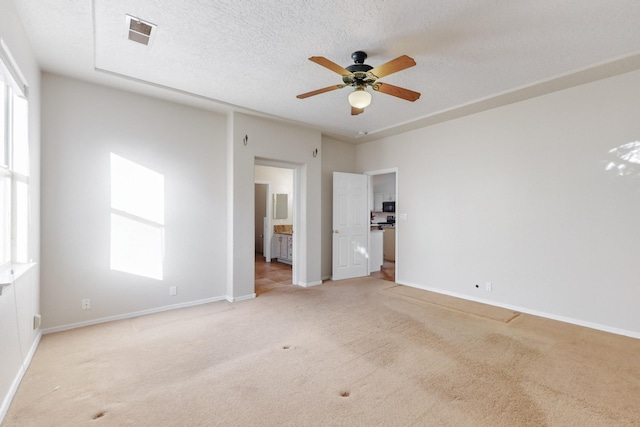 unfurnished bedroom featuring a textured ceiling, light colored carpet, and ceiling fan