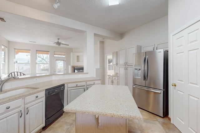 kitchen with ceiling fan, sink, stainless steel fridge with ice dispenser, black dishwasher, and a kitchen island