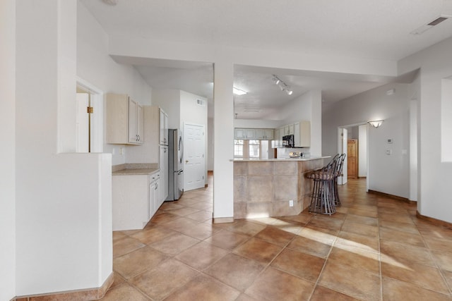 kitchen featuring stainless steel fridge, light tile patterned flooring, and rail lighting