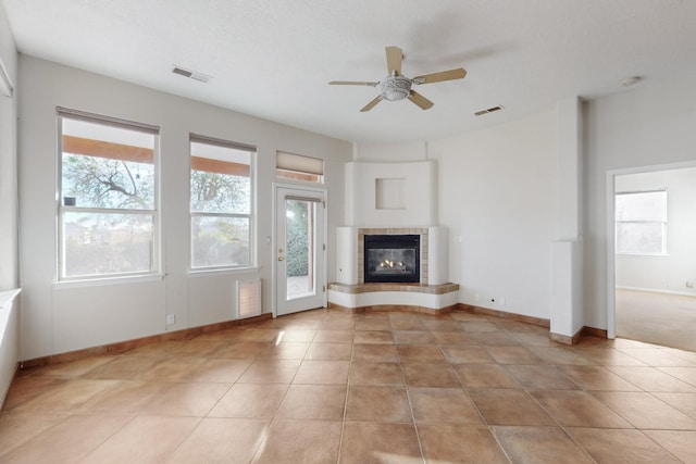 unfurnished living room featuring ceiling fan, light tile patterned floors, and a fireplace