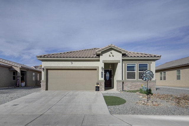 mediterranean / spanish-style home with a tile roof, stucco siding, a garage, stone siding, and driveway