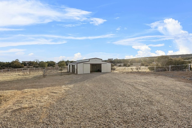 view of yard with gravel driveway, a detached garage, fence, an outdoor structure, and a pole building