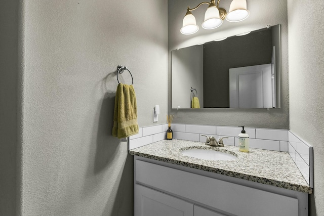 bathroom with a notable chandelier, vanity, and a textured wall