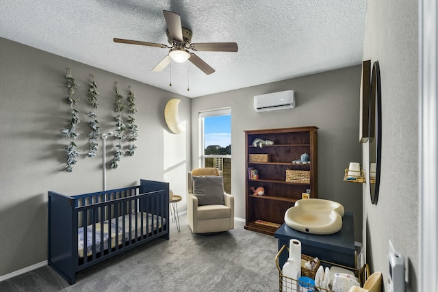 bedroom featuring a wall unit AC, carpet, baseboards, a crib, and a textured ceiling