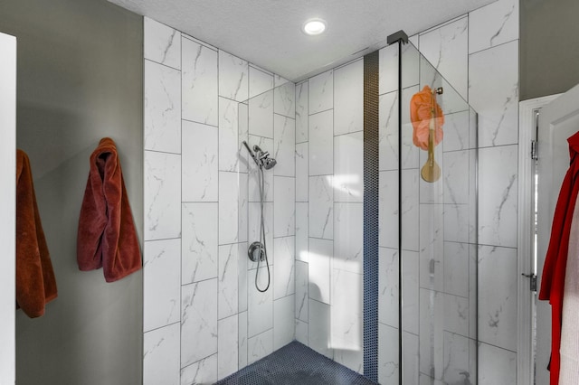 bathroom with a textured ceiling and tiled shower