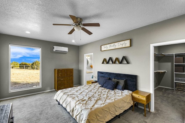 bedroom with a ceiling fan, baseboards, a wall mounted AC, a spacious closet, and carpet flooring