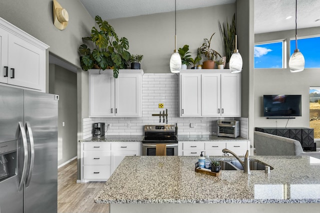 kitchen with a sink, decorative backsplash, appliances with stainless steel finishes, and white cabinets