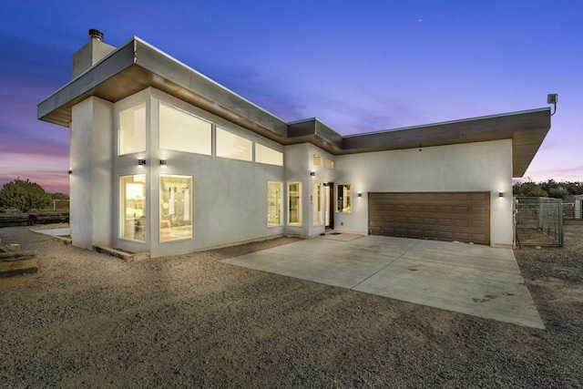 view of front of house with a garage, concrete driveway, a chimney, and stucco siding