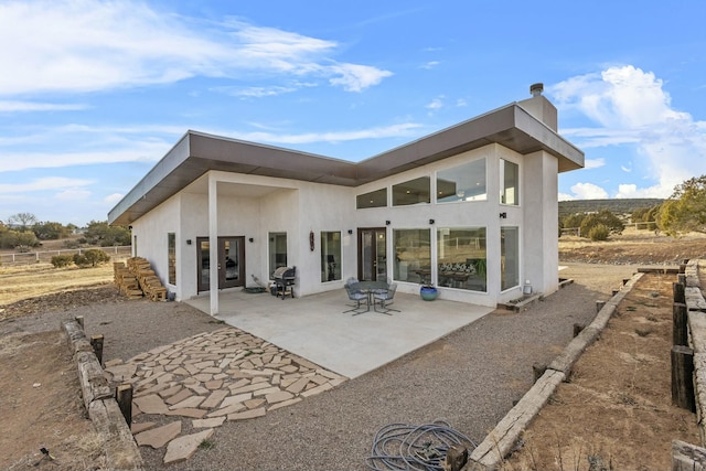 rear view of house featuring a patio area and stucco siding