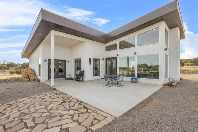 rear view of property featuring a patio area, french doors, and stucco siding