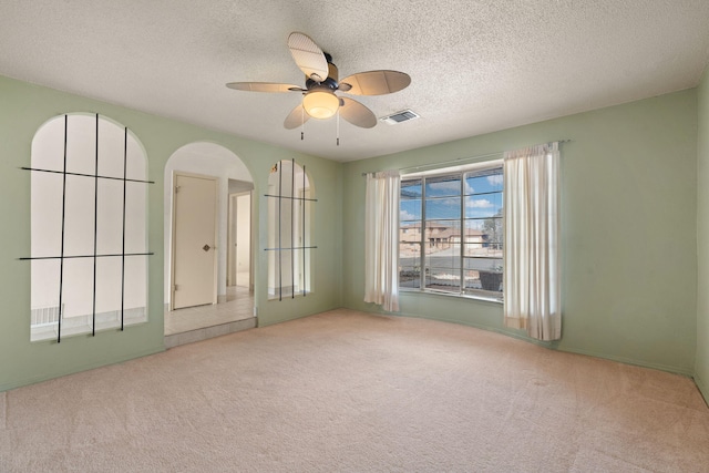 carpeted empty room with ceiling fan and a textured ceiling