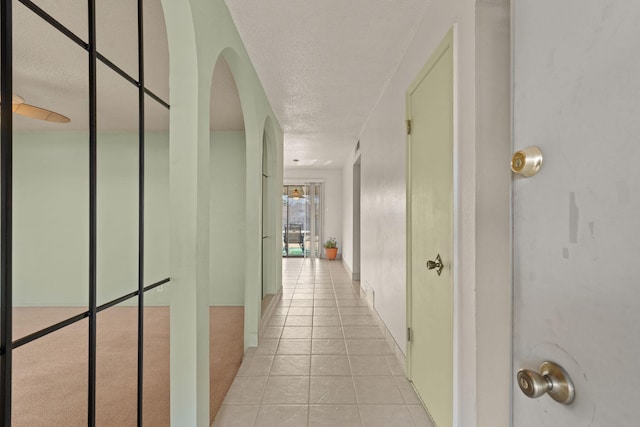 hallway featuring light tile patterned floors and a textured ceiling