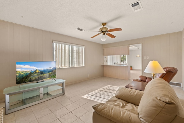 living room with ceiling fan, light tile patterned floors, a healthy amount of sunlight, and a textured ceiling