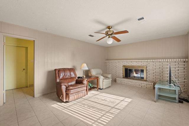 sitting room featuring ceiling fan, light tile patterned floors, and a brick fireplace