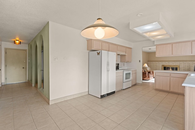 kitchen featuring light brown cabinetry, light tile patterned flooring, decorative light fixtures, and white appliances