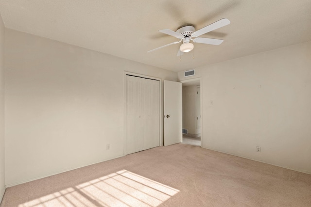 unfurnished bedroom featuring ceiling fan, light carpet, and a closet