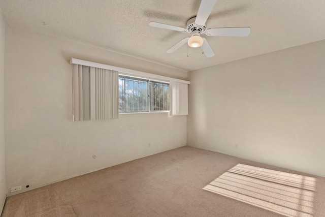 empty room featuring ceiling fan, a textured ceiling, and light carpet