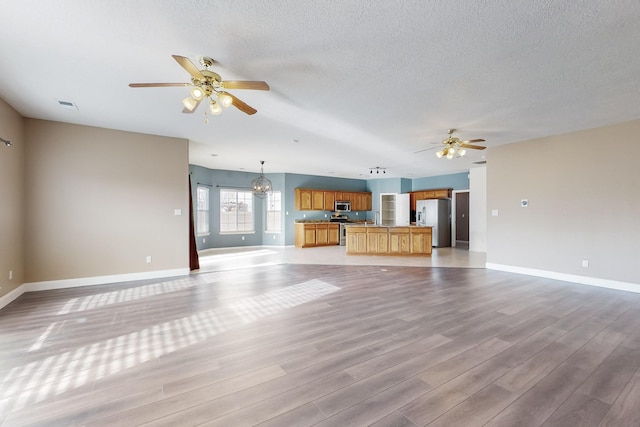 unfurnished living room with a textured ceiling, light wood-type flooring, and ceiling fan