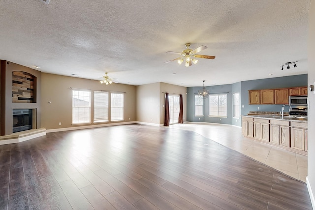 unfurnished living room featuring plenty of natural light, dark hardwood / wood-style floors, and ceiling fan with notable chandelier