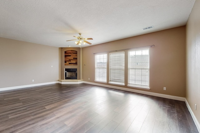 unfurnished living room featuring ceiling fan, a fireplace, wood-type flooring, and a textured ceiling