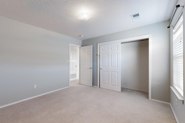 unfurnished bedroom with light carpet, a closet, and a textured ceiling