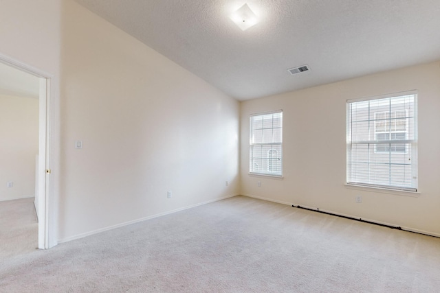 carpeted empty room with a textured ceiling and vaulted ceiling