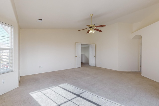 empty room featuring light colored carpet, a wealth of natural light, and vaulted ceiling