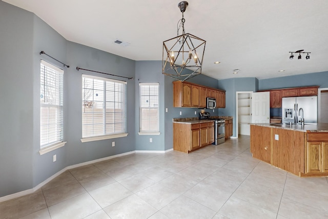 kitchen with appliances with stainless steel finishes, a kitchen island with sink, decorative light fixtures, an inviting chandelier, and light tile patterned flooring