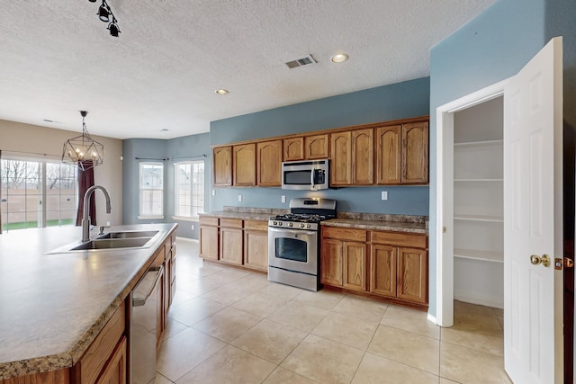 kitchen featuring sink, a notable chandelier, pendant lighting, a center island with sink, and appliances with stainless steel finishes