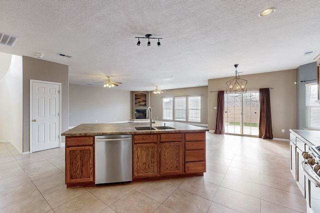 kitchen featuring stainless steel dishwasher, ceiling fan with notable chandelier, sink, a center island with sink, and hanging light fixtures