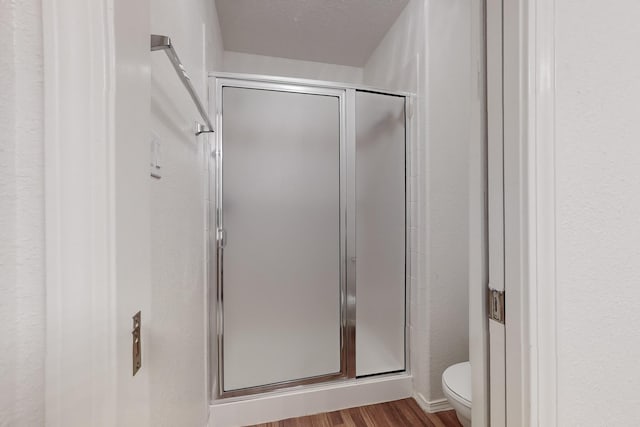 bathroom featuring hardwood / wood-style flooring, toilet, and walk in shower